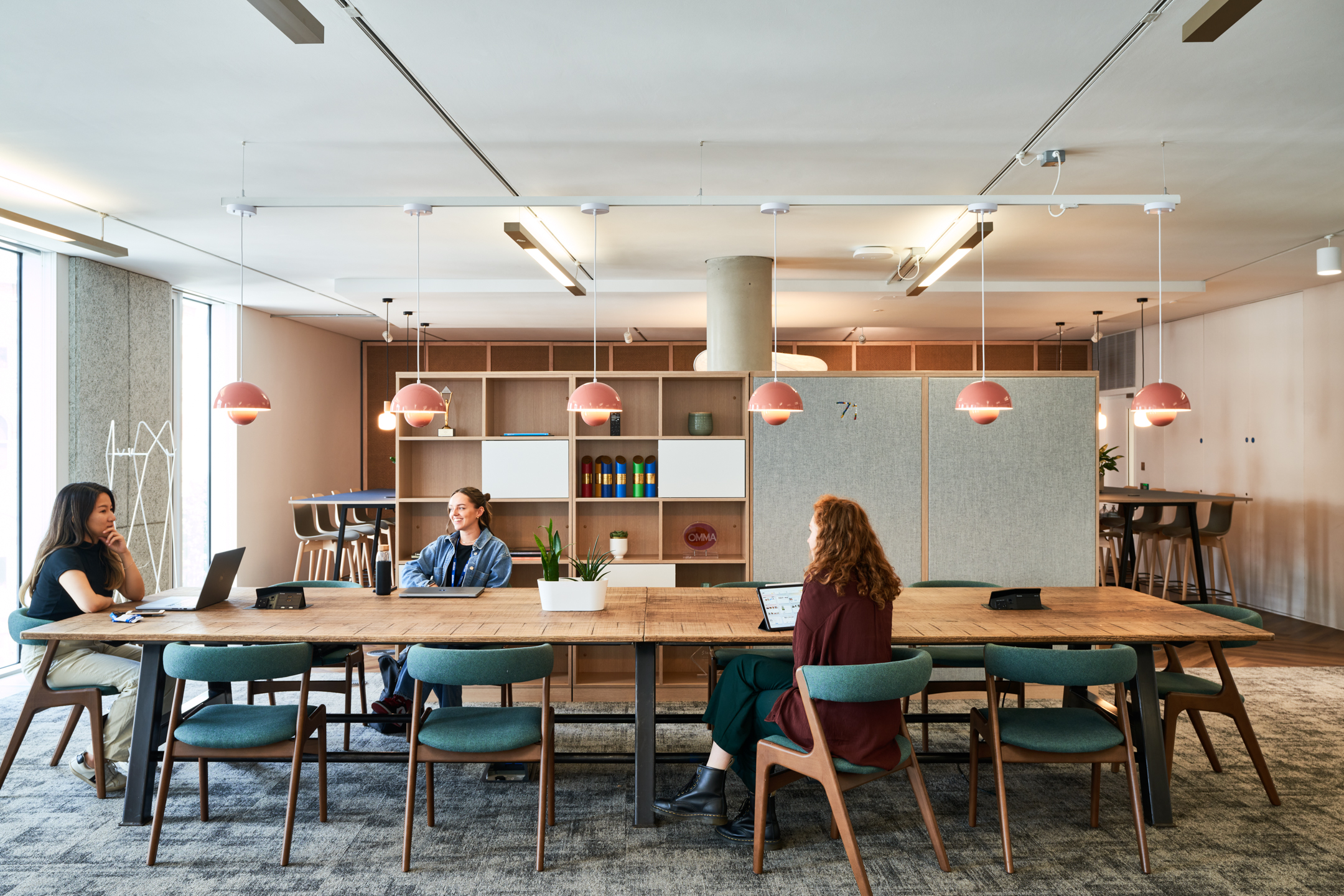 A collaborative group workspace at Publicis Sapient’s office, featuring a large wooden table, modern lighting, and comfortable seating.