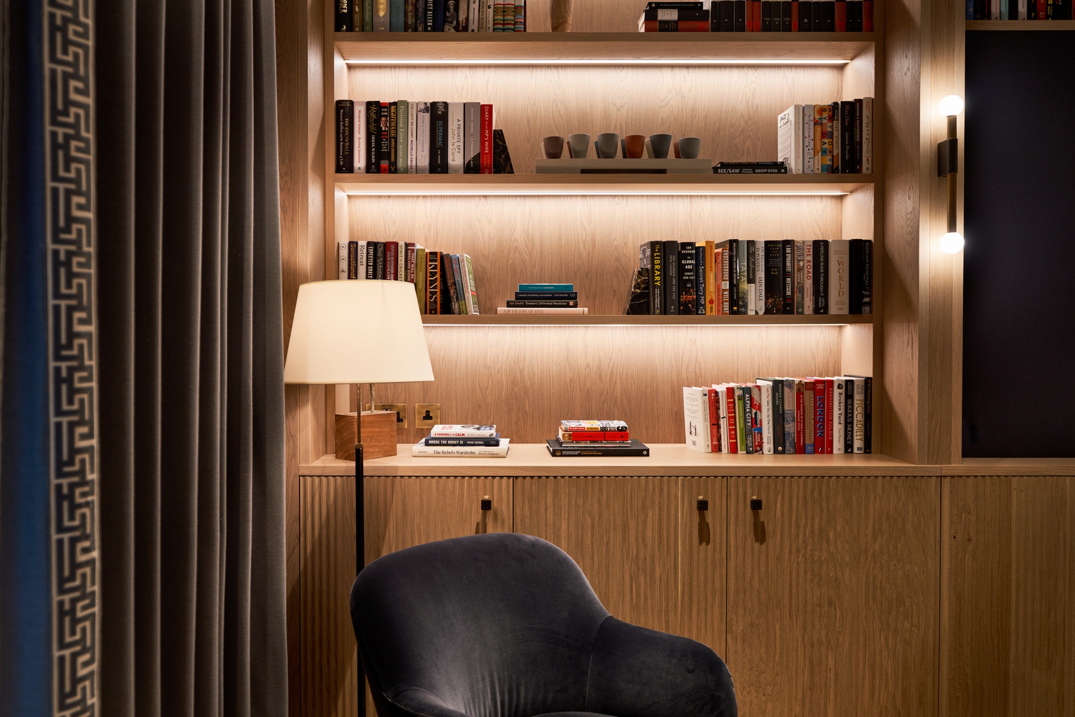 A warm, inviting reading room at Asset Management Firm, featuring built-in bookshelves and soft lighting designed by Modus Workspace.