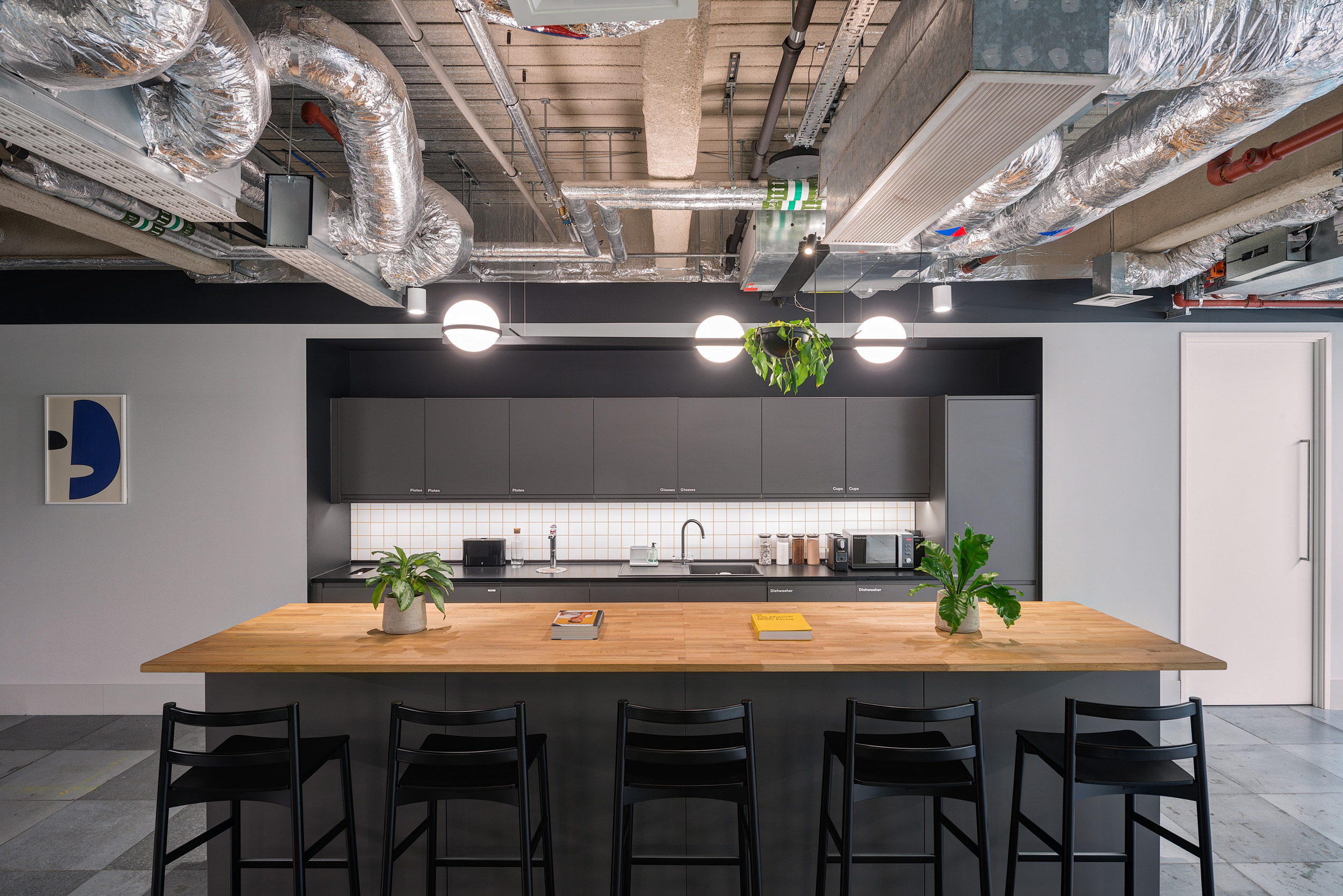 A sleek, contemporary teapoint within British Land's 3 Finsbury Avenue office, designed by Modus Workspace. The kitchen features a large wooden countertop, industrial-style lighting, and modern appliances, perfect for informal meetings and breaks.