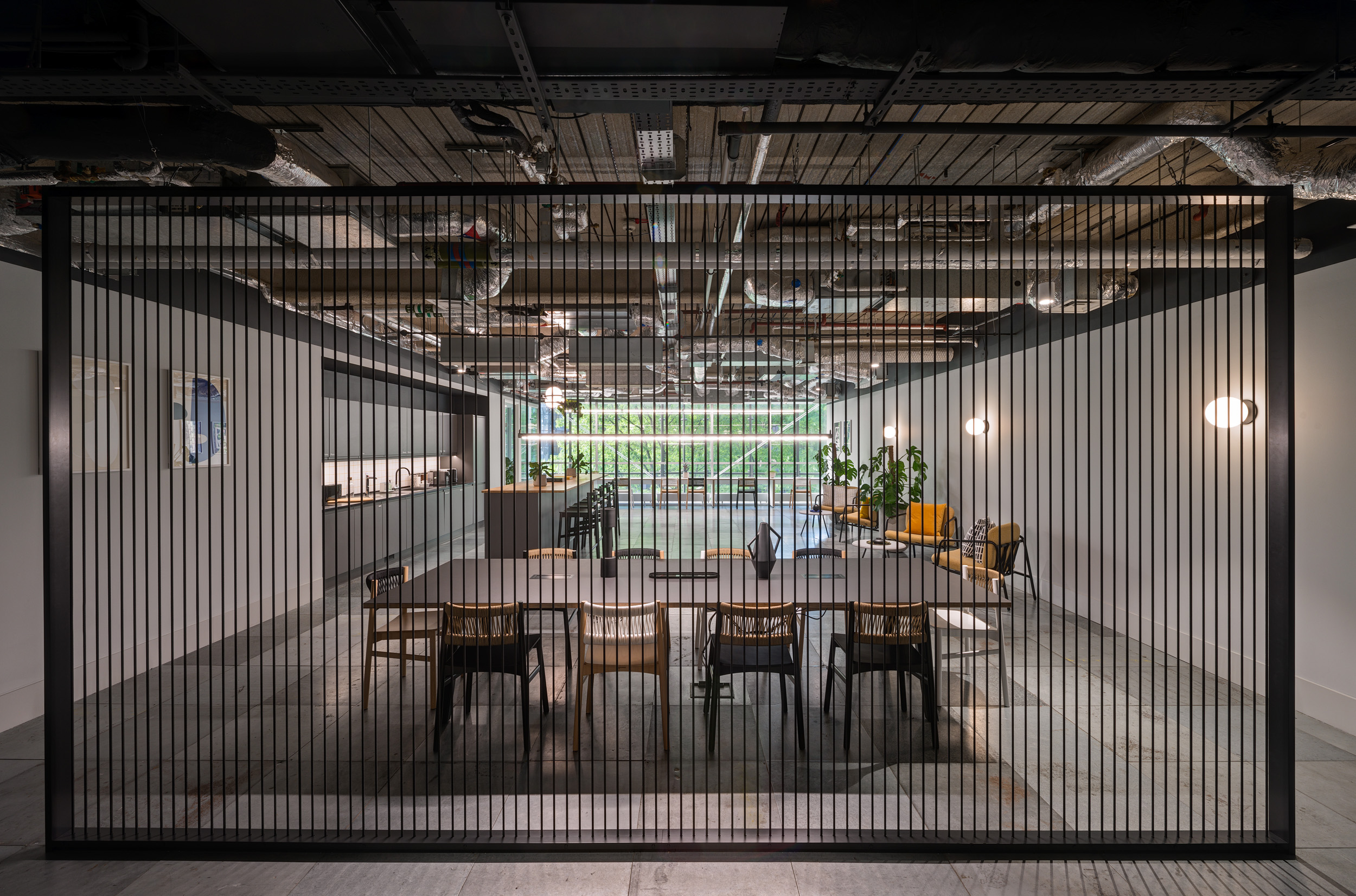 An open, collaborative workspace at British Land's 3 Finsbury Avenue office, designed by Modus Workspace. The space is divided by vertical slats, providing a sense of separation while maintaining an open-plan feel, with ample seating and natural light.