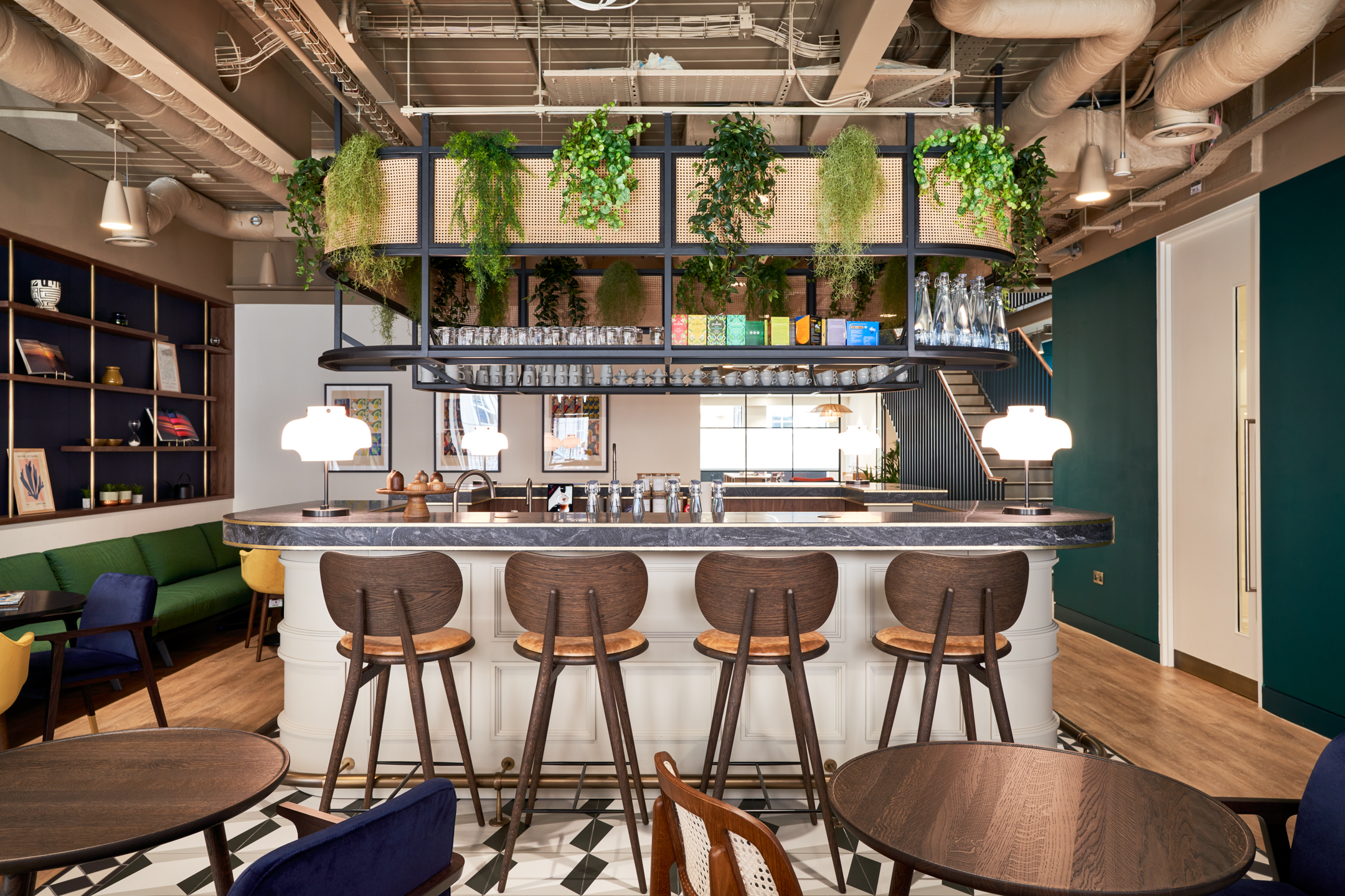 A chic coffee bar and lounge area at a private equity firm in Marylebone, featuring natural wood and greenery. The space, designed by Modus Workspace, offers a relaxing setting for informal meetings and breaks.