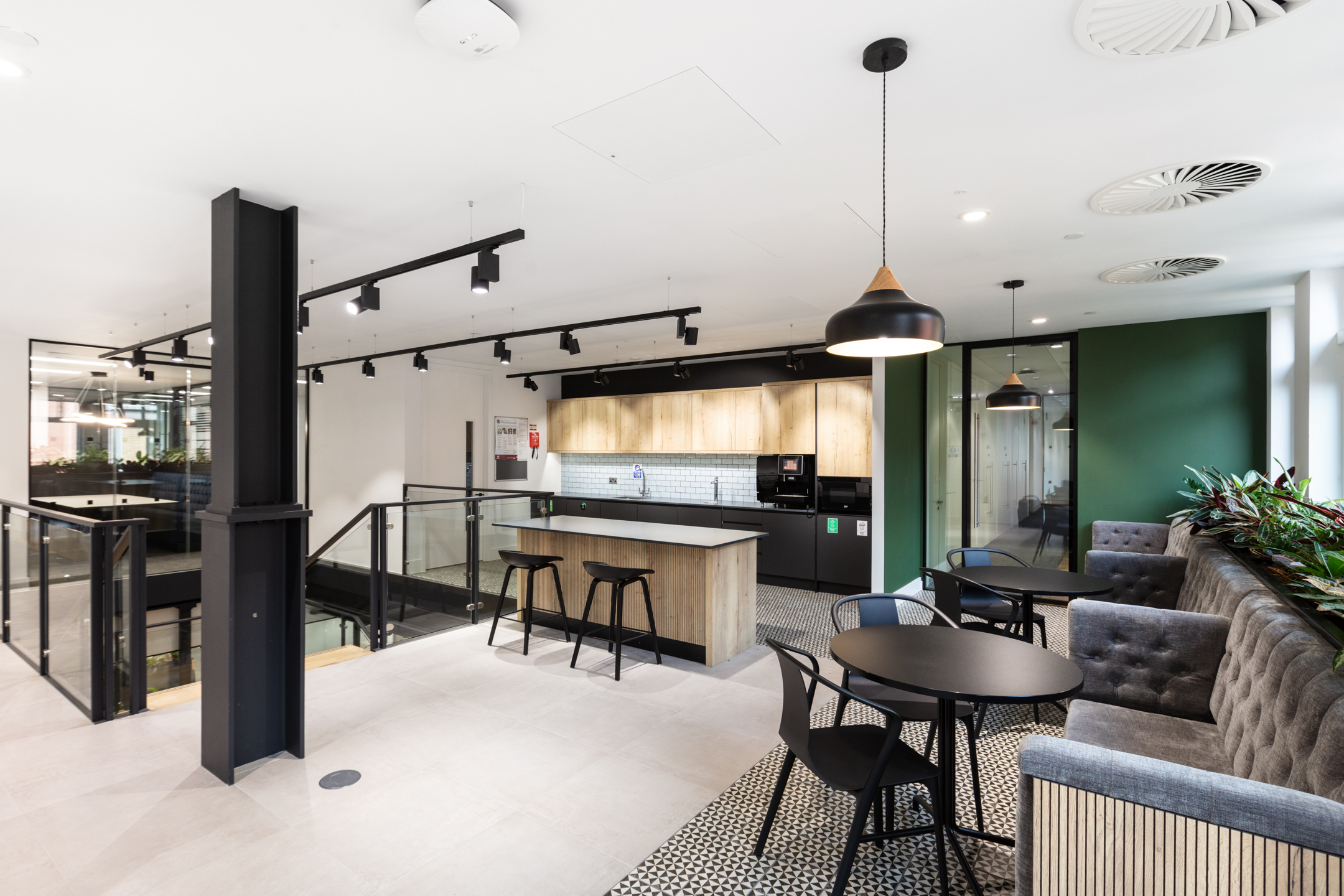 A spacious teapoint and lounge area with modern decor, featuring a sleek island counter, booth seating, and light wooden finishes. Designed by Modus Workspace, the space is ideal for casual dining or impromptu meetings.