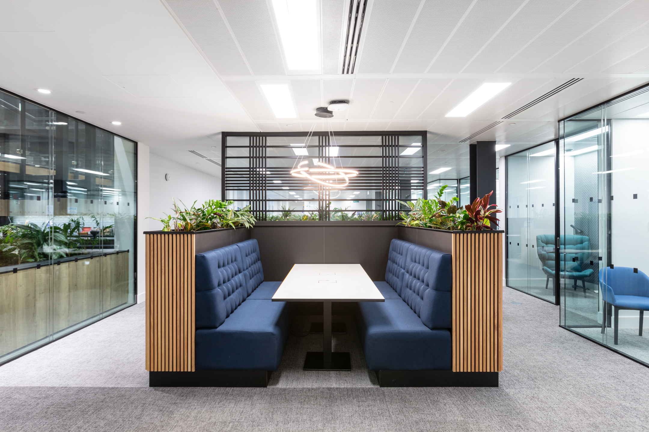 A cosy and private booth seating area at Russell Reynolds, designed by Modus Workspace. Featuring padded seating, soft lighting, and integrated planters, the space offers a comfortable and semi-private area for discussions.