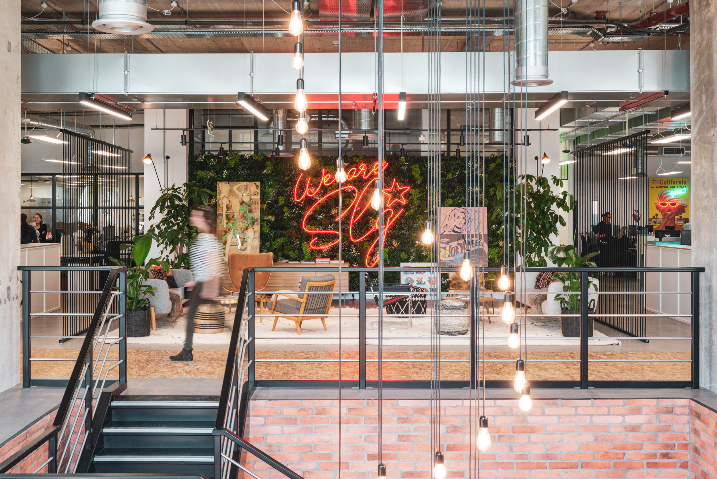 The vibrant breakout space at SLG Brands featuring bold design elements, greenery, and a neon sign, reflecting the company's creative and dynamic culture