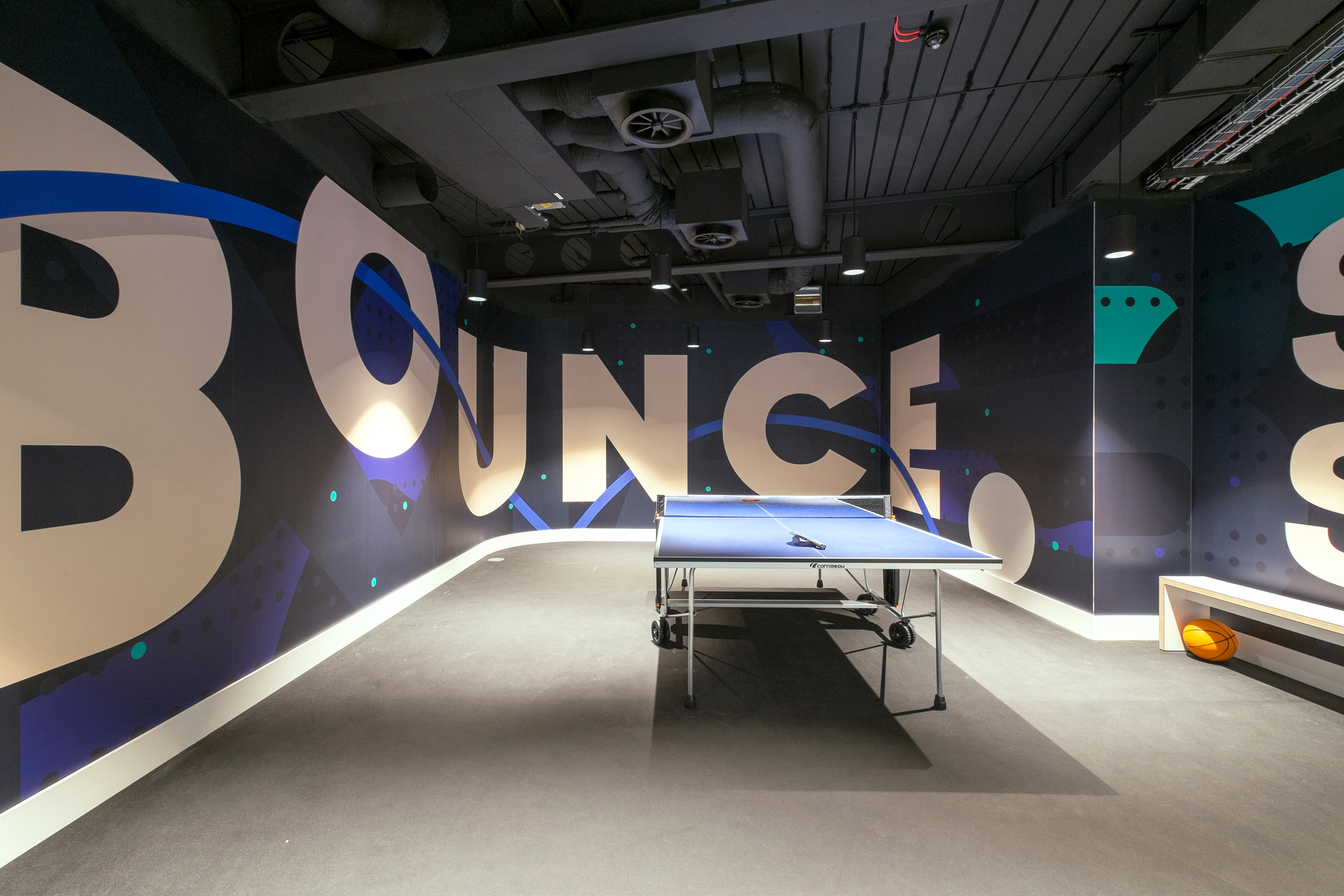 The reception desk at Skyscanner’s office has a wood-accented counter, overhead plants, and a digital display framed by overhead greenery and modern lighting.