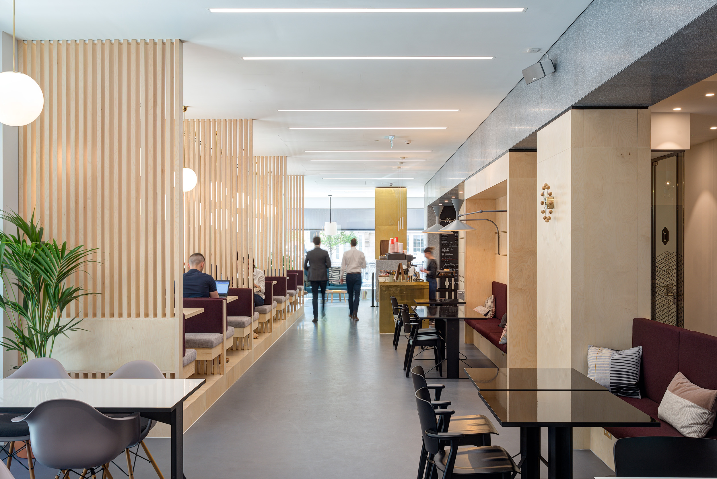 Café area at Spaces Harley Building in Fitzrovia, featuring light wooden slatted dividers and maroon upholstered booths. 