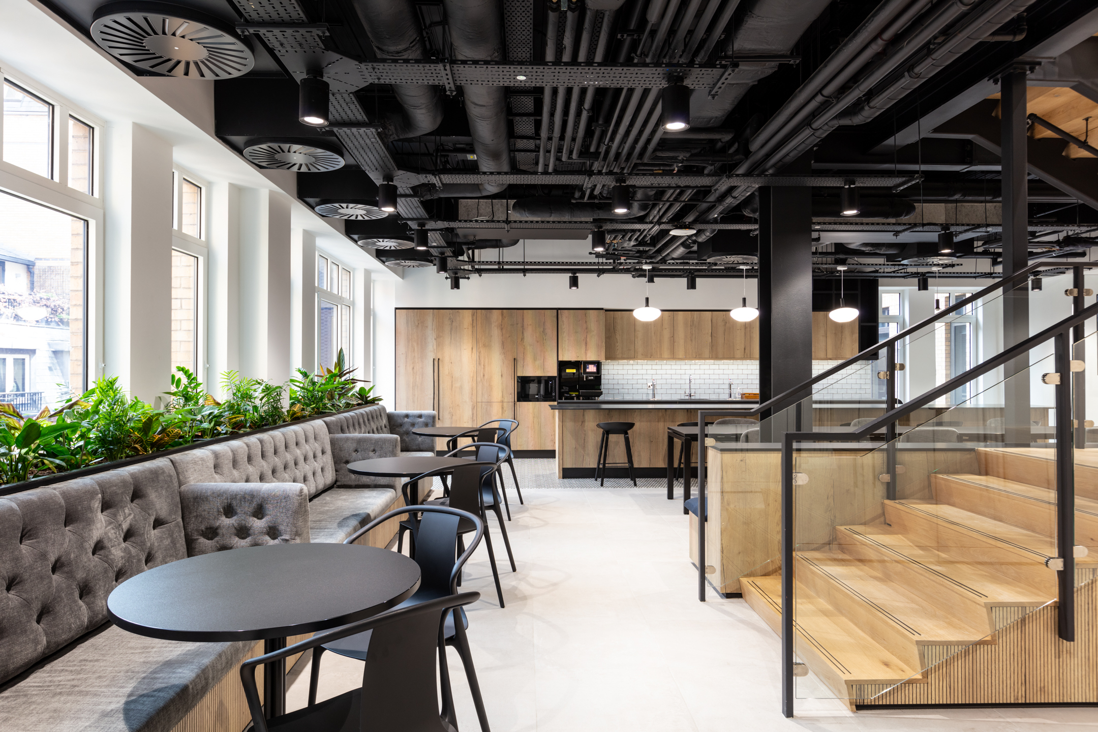 Stylish breakout area designed by Modus for Russell Reynolds, featuring plush seating, natural light, greenery, and a modern teapoint.