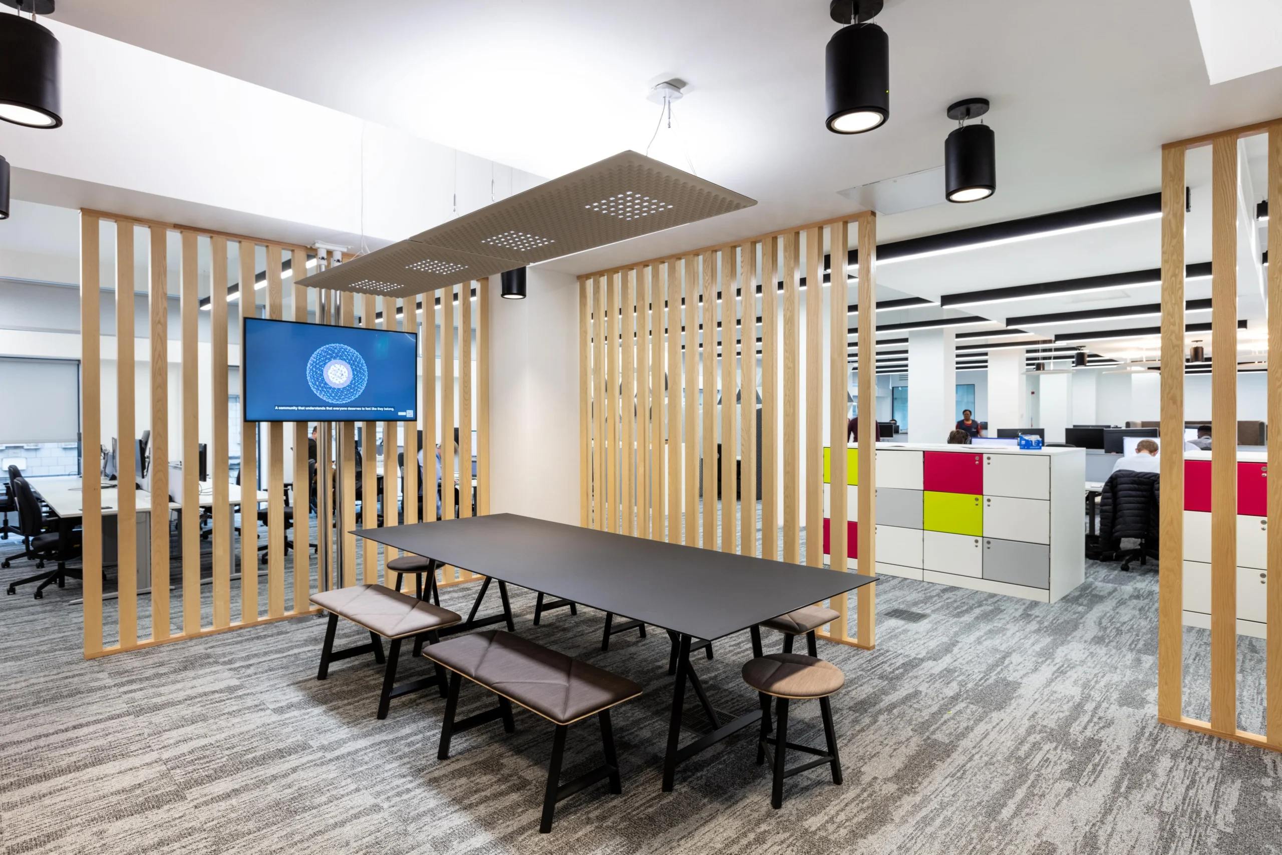 Breakout area for Atkins, with a central table, surrounding wooden dividers, and vibrant lockers.