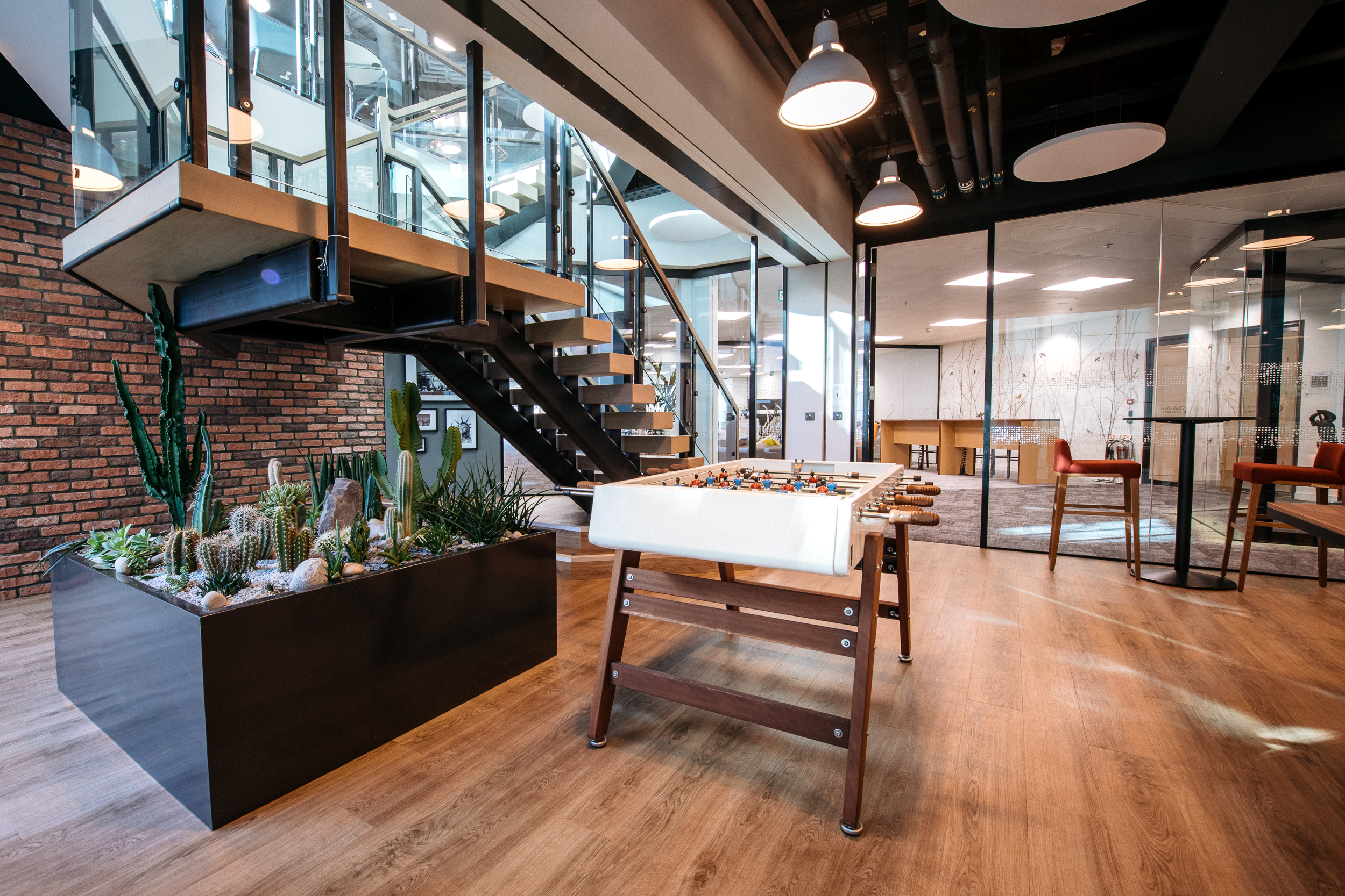 A central staircase with glass railings and a cacti display in the Charles River Associates office designed by Modus Workspace.