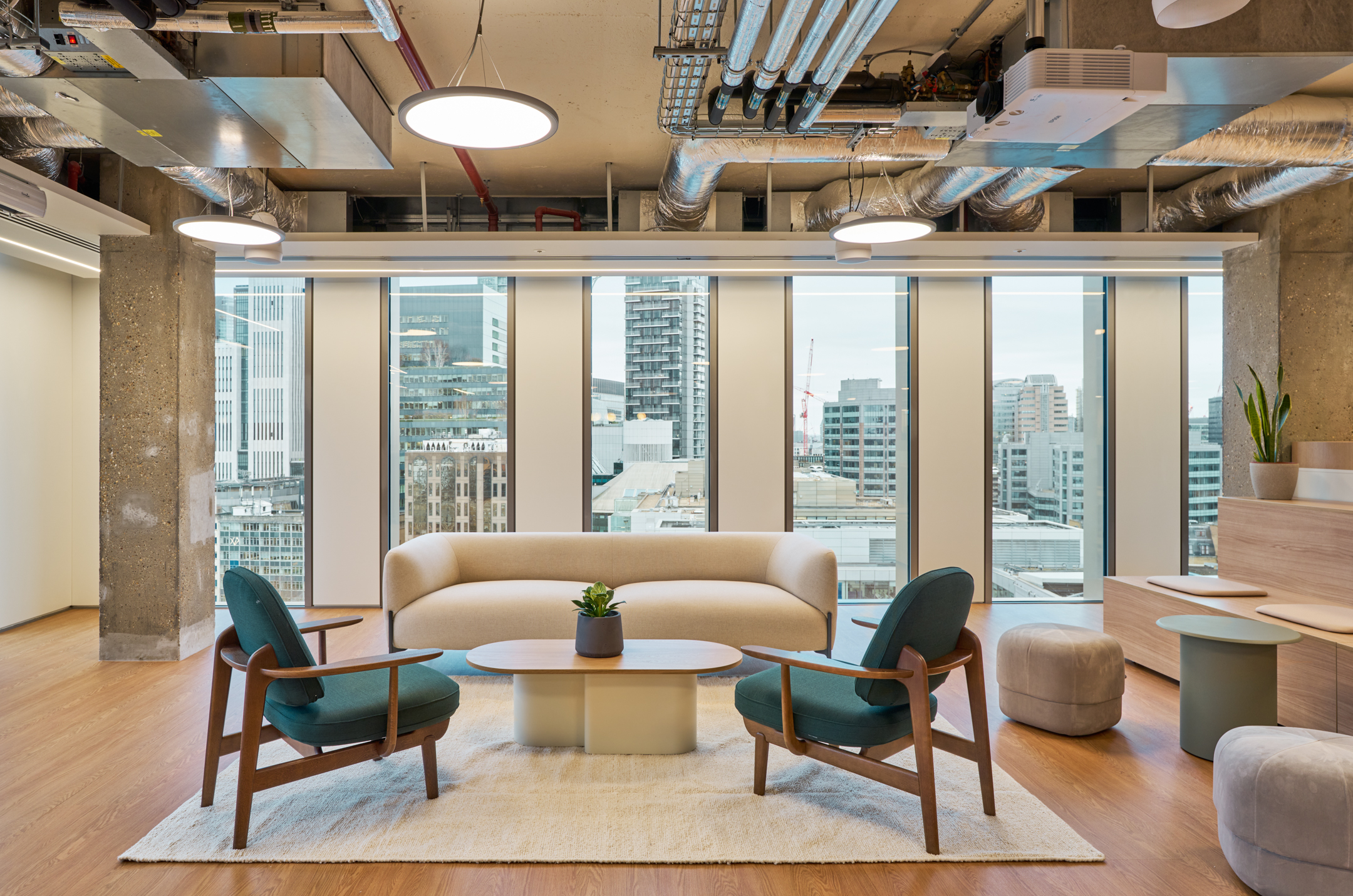 A cosy seating area in Salesloft’s London office at the HYLO building, featuring modern furniture with a cityscape backdrop, designed for a welcoming and comfortable atmosphere.