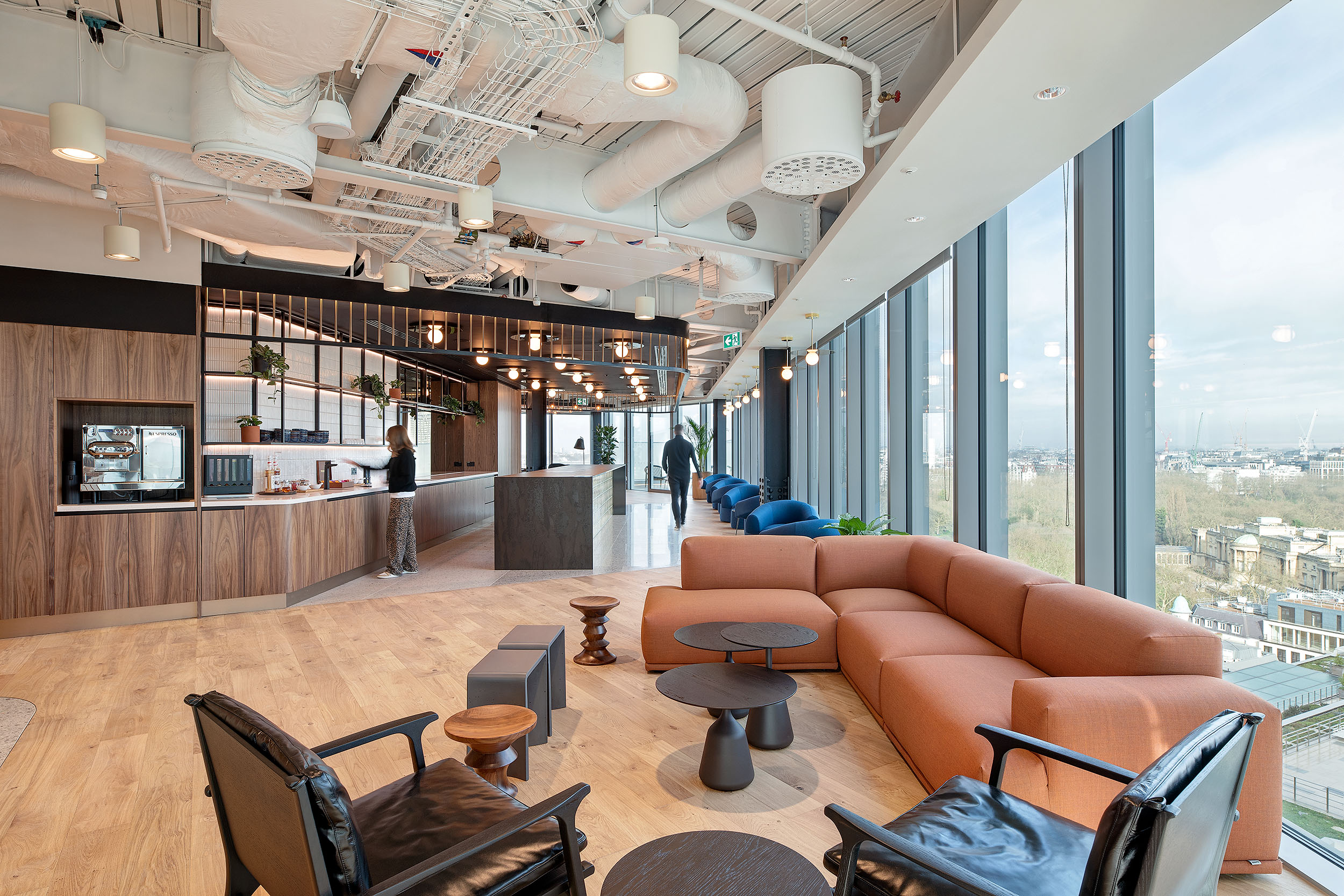 International Technology and Data Firm, featuring an open-plan lounge with contemporary seating, a sleek coffee station with wood finishes, and floor-to-ceiling windows offering expansive city views.